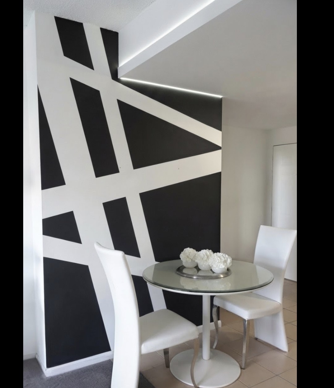 Same dining area wall painted with a bold black and white geometric mural